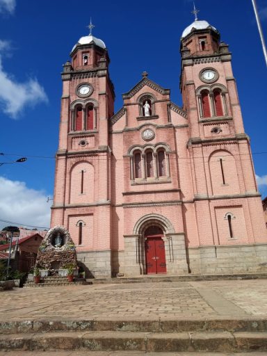 Église rose à deux tours, avec un ciel bleu en arrière-plan.